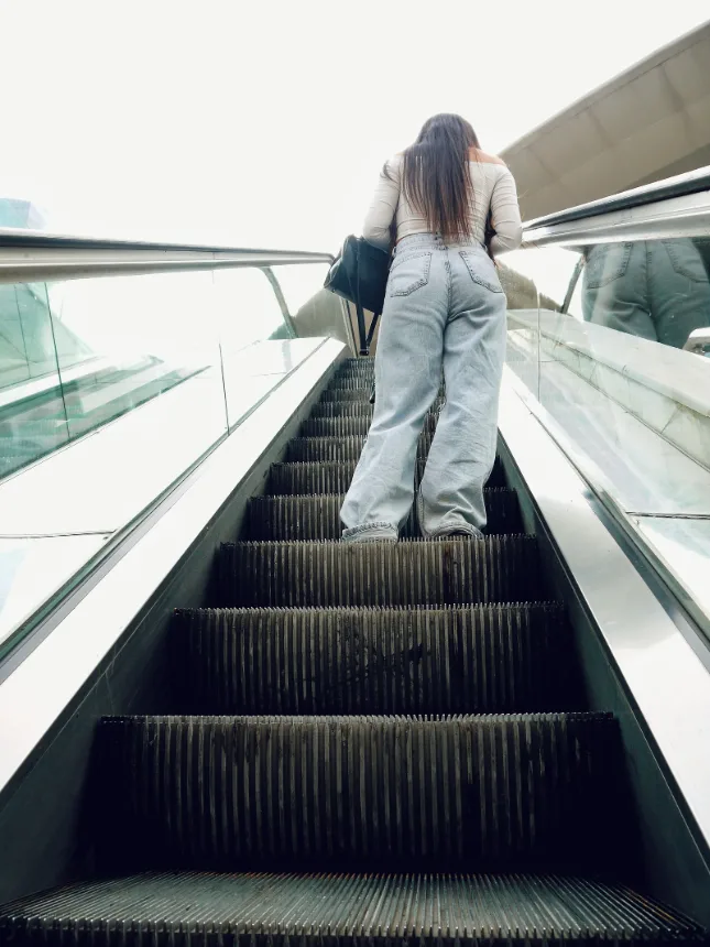 Pessoa subindo a escada rolante dentro de um shopping center