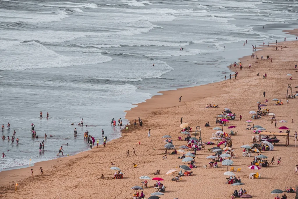 Faixa de areia cheia de banhistas e guarda-sois vista do alto no verao
