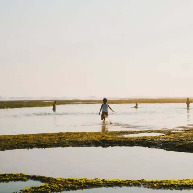 Praia de agua rasa e calma com pessoas caminhando no raso