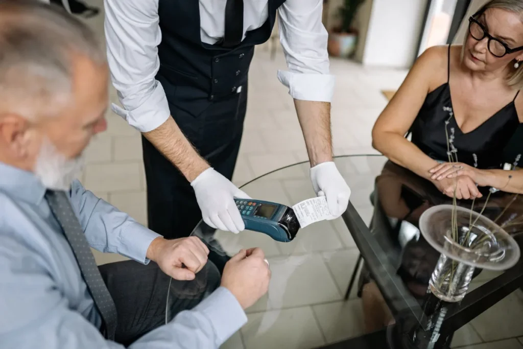 Cliente pagando a conta na maquininha de cartão à mesa