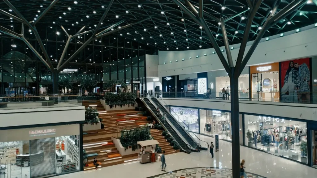 Interior de um shopping com escadas rolantes e lojas