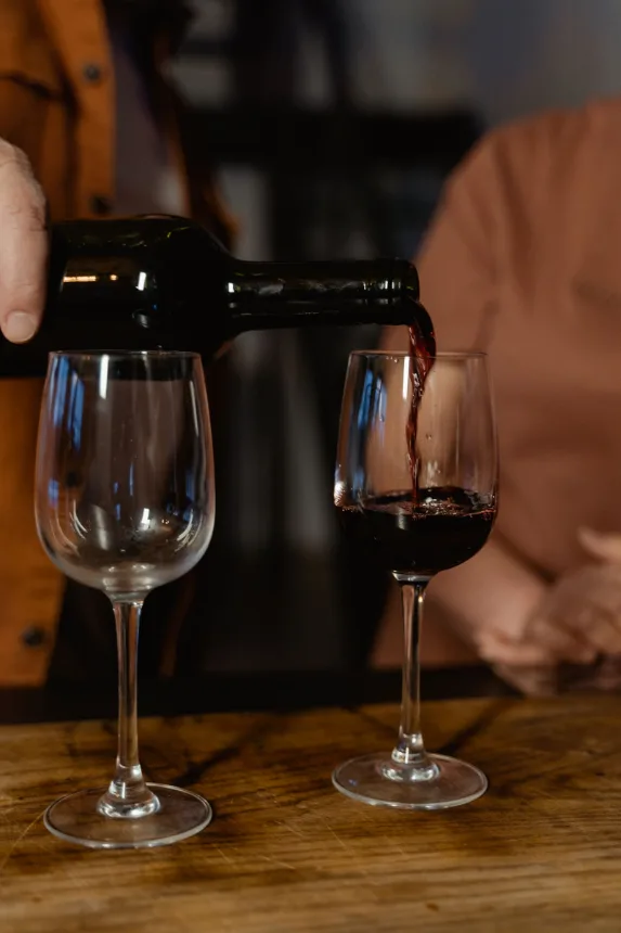 Vinho tinto sendo servido em duas taças sobre a mesa