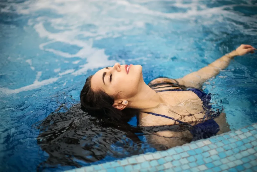 Mulher boiando de olhos fechados em uma piscina de agua morna