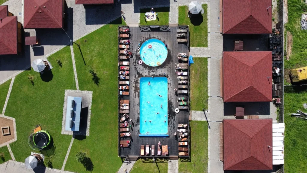 Complexo de piscinas termais visto do alto, cercado por gramado e cabanas