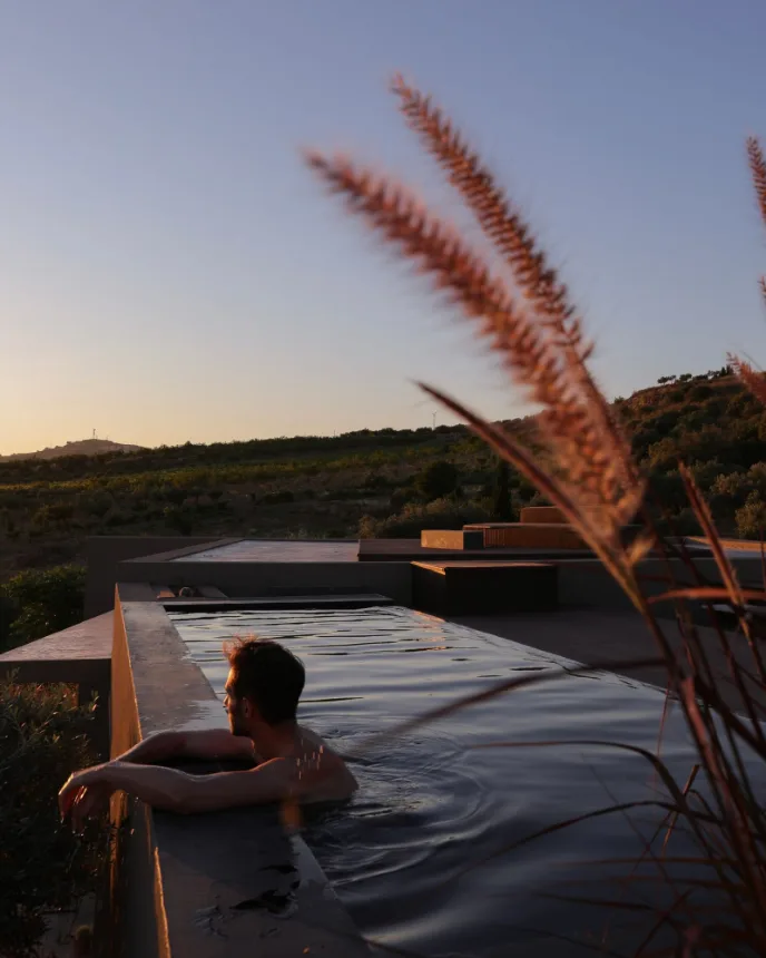 Homem relaxando em uma piscina ao ar livre no fim da tarde