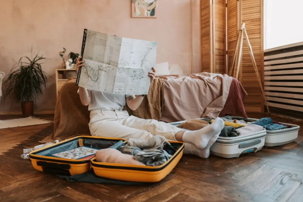 Malas abertas no chao e um mapa aberto durante o planejamento de uma viagem