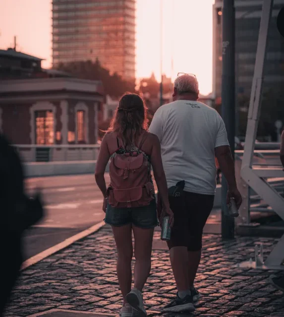 Casal caminhando por uma rua de pedra no fim da tarde