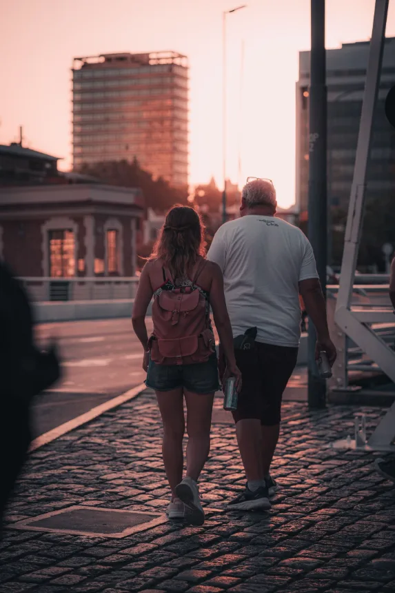 Casal caminhando por uma rua de pedra no fim da tarde
